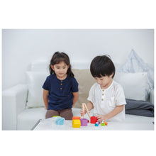 Load image into Gallery viewer, 2 young children around a table playing with the plantoys beehives sorting and stacking game
